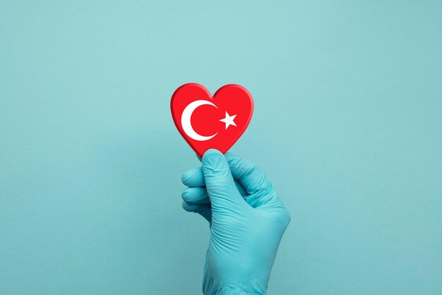 Руки в защитных хирургических перчатках держат сердце флага Турции