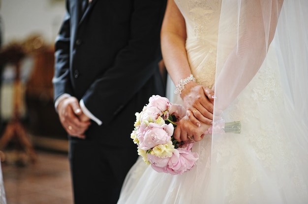 Hands of wedding couple at the church