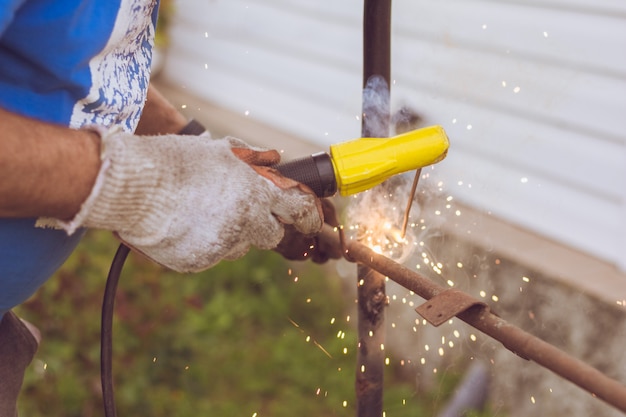 Photo hands of a welder close up with fire and sparks