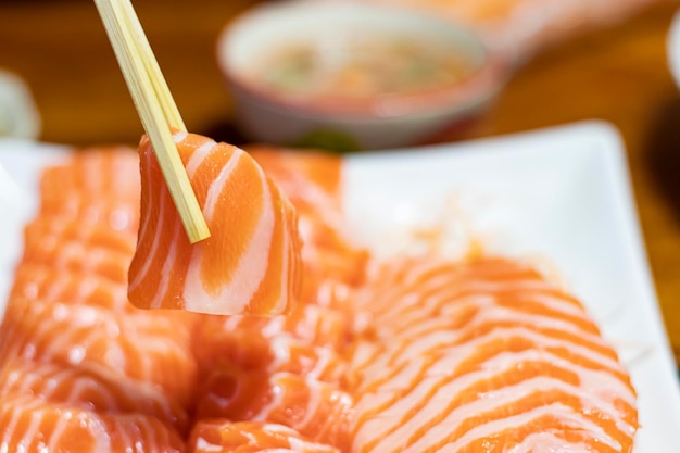 The hands were holding the chopsticks to hold the salmon sashimi with copy space