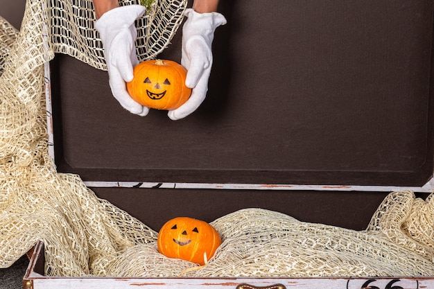 Hands in white gloves take out a pumpkin from a brown chest