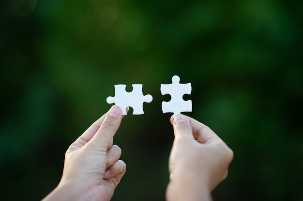 Hands and white jigsaw puzzle pieces