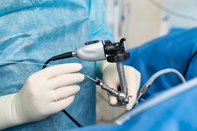 Hands in white latex gloves using special modern instruments while providing complex operation Modern medicine Cropped photo