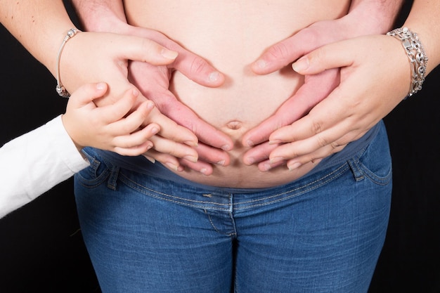 hands of the whole family on the belly of the pregnant woman