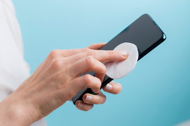 Hands wipe the phone with a disinfectant cotton swab.