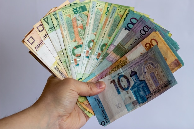 Mani con denaro bielorusso su sfondo bianco valuta bielorussa su sfondo bianco