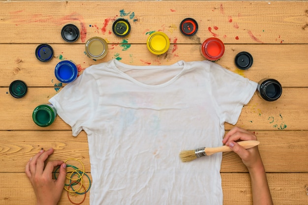 Photo hands with a brush and paint paint a white tshirt