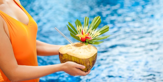 Hands with coconut on the background of the pool