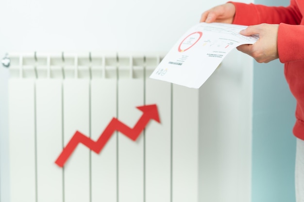 Photo hands with electricity bill closing heating radiator due to price hike energy crisis