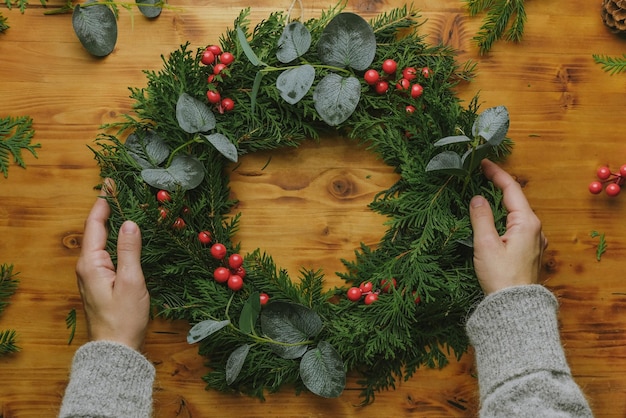 Hands with evergreen Christmas wreath