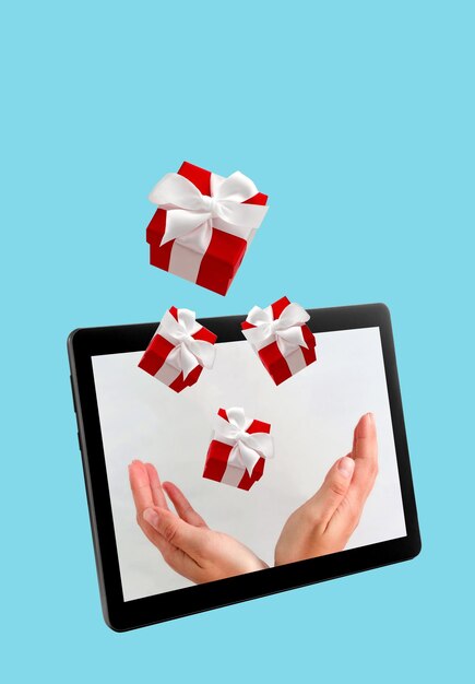 Hands with flying gift boxes on digital tablet screen on blue background