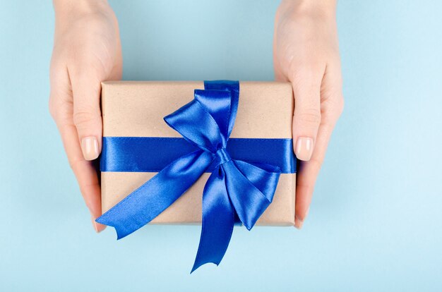 Hands with gift box  present with ribbon and bow.