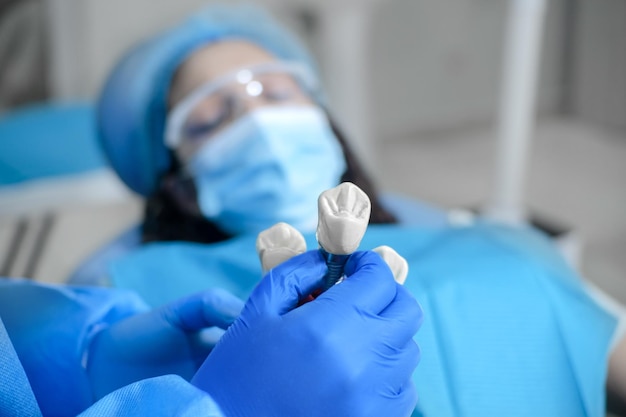 Hands with glove showing a model of a dental implant