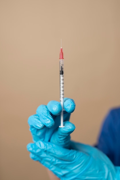 Photo hands with gloves holding syringe