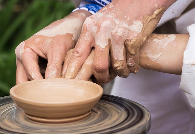 Mani con l'aiuto di un maestro lavora su un tornio da vasaio