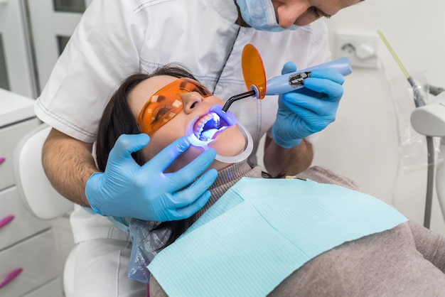 Hands with lamp and patient in protective glasses