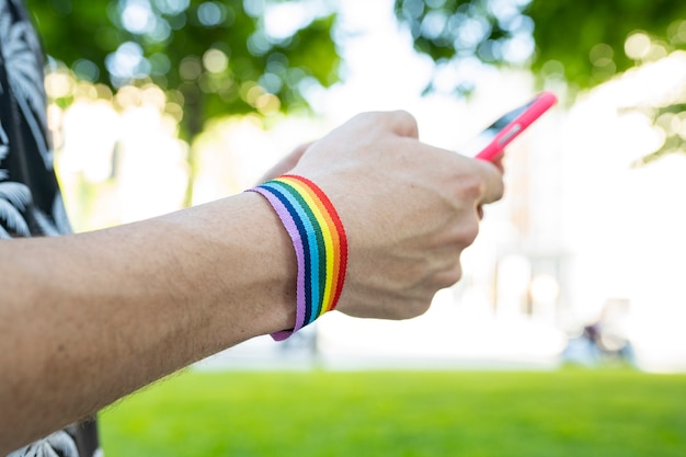 Hands with LGBT bracelet with a mobile