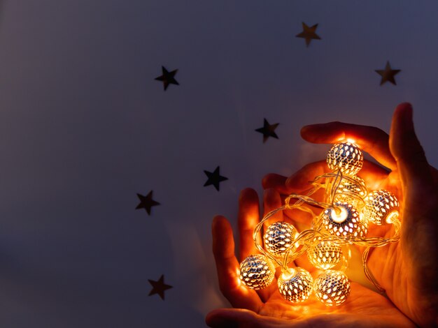 Фото Руки с лампочками в форме сердца. металлические лампочки светятся в темноте.