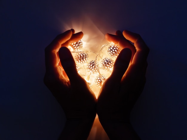 Hands with light bulbs in shape of heart. 