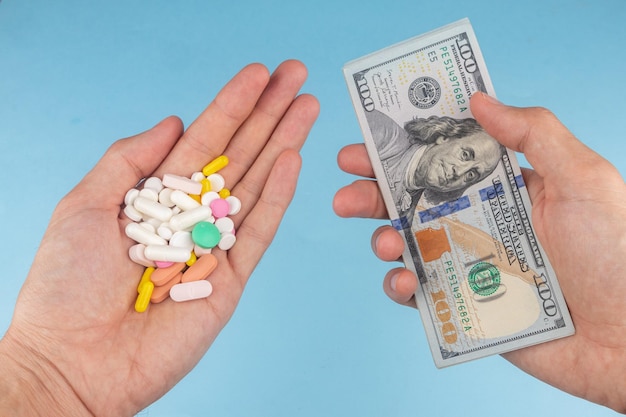 Hands with money and pills on blue background concept of expensive medicine