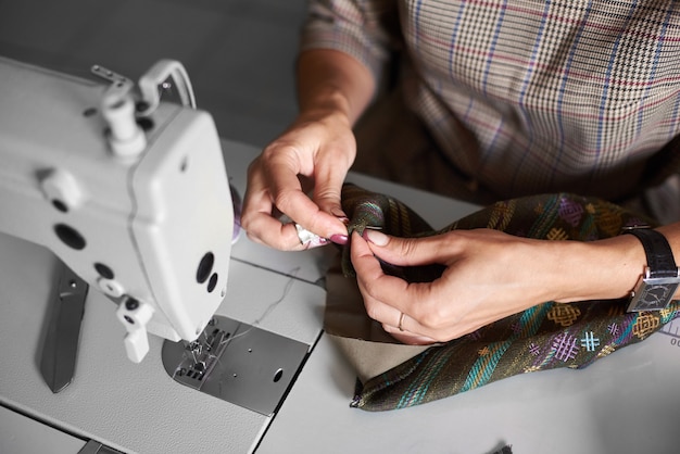 Hands with needle stitching together garment details before sewing