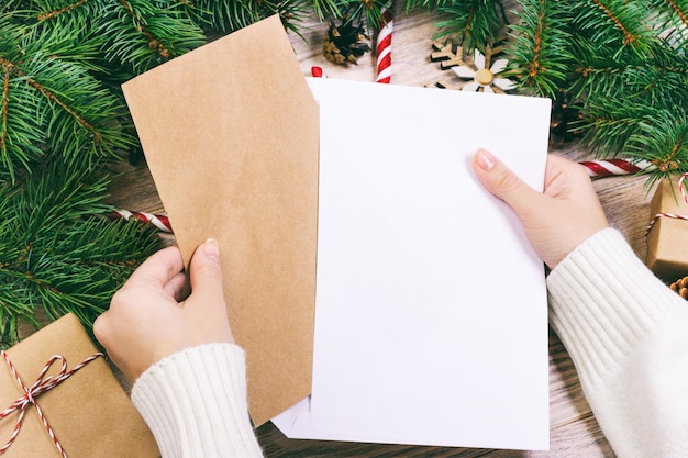 Hands with notebook and an envelop for letter. A girl is ready to send a letter with wishes to Santa Claus. Toned.