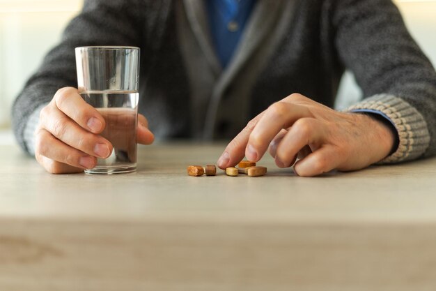 Hands with pills senior man hands holding medical pill and glass of water mature old senior