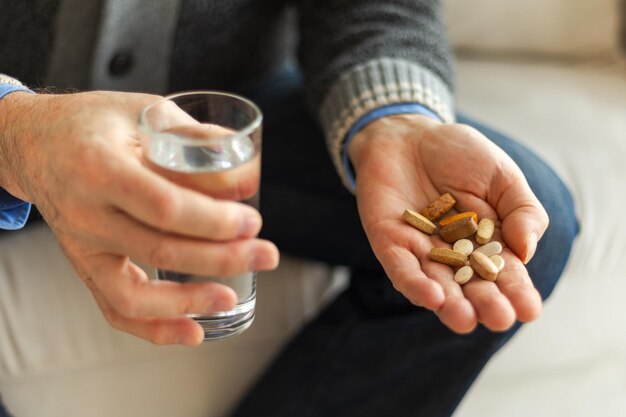 Photo hands with pills senior man hands holding medical pill and glass of water mature old senior