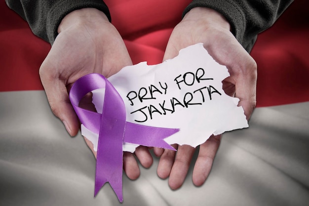 Photo hands with ribbon and text of pray for jakarta