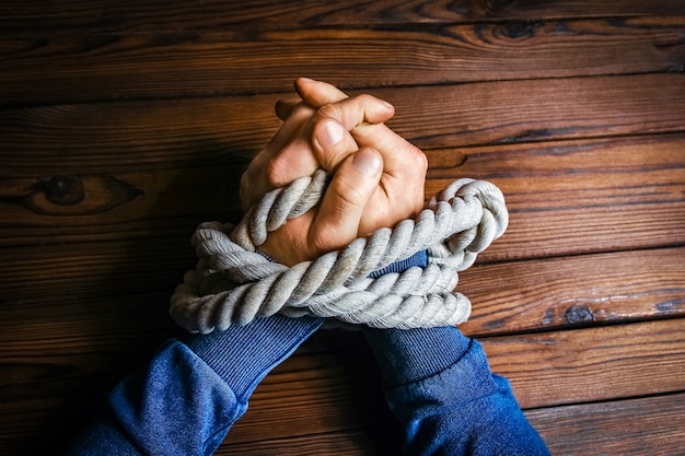 Hands with a rope on a wooden background