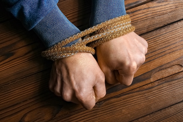 Hands with a rope on a wooden background