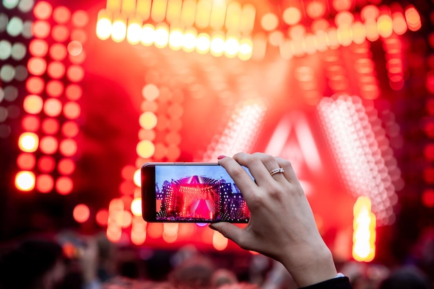 Hands with a smartphone records live music festival