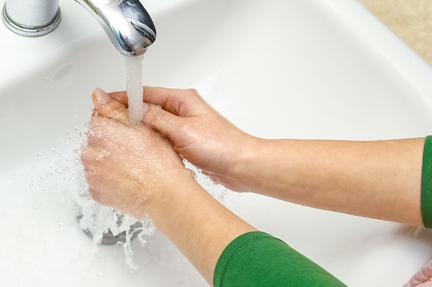 A Hands with soap are washed under the tap with water. Clean from infection and dirt and virus. At home or in the hospital ablution office.