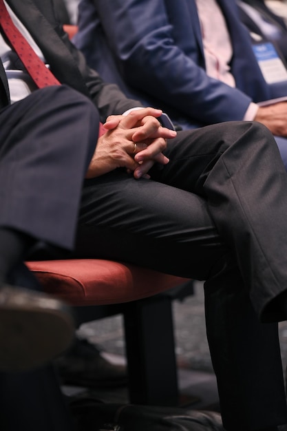 Hands with suit, rest on the legs the a person