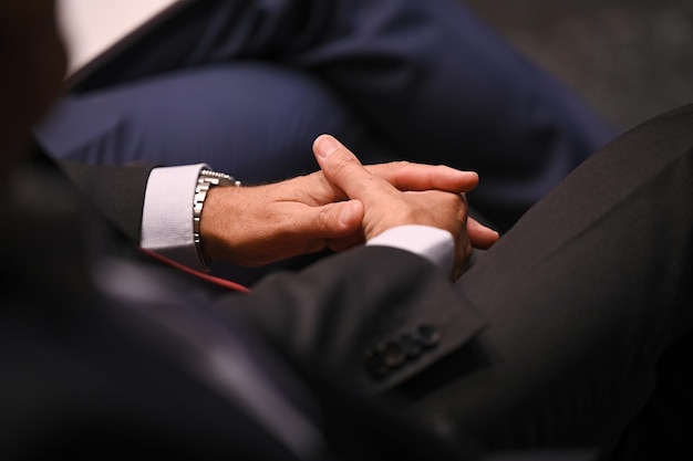 Hands with suit, rest on the legs the a person