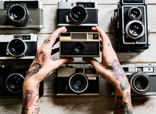 Mani con tatuaggio tenendo una macchina fotografica