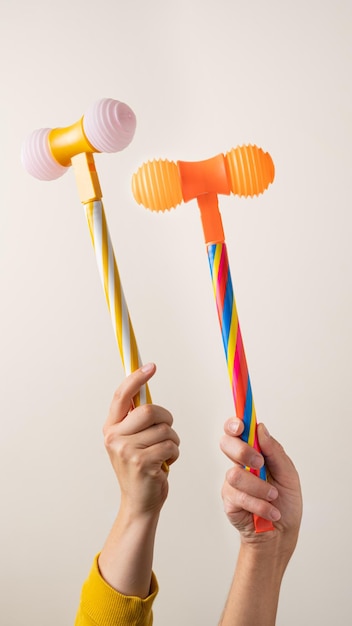 Hands with toy hammers against light background