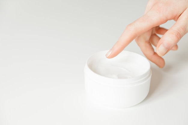 Hands of a woman about to touch moisturizer cream in jar