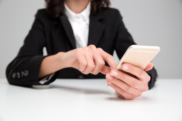 Mani di donna in giacca nera usando il cellulare