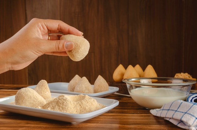 Hands of woman breading brazilian croquette 