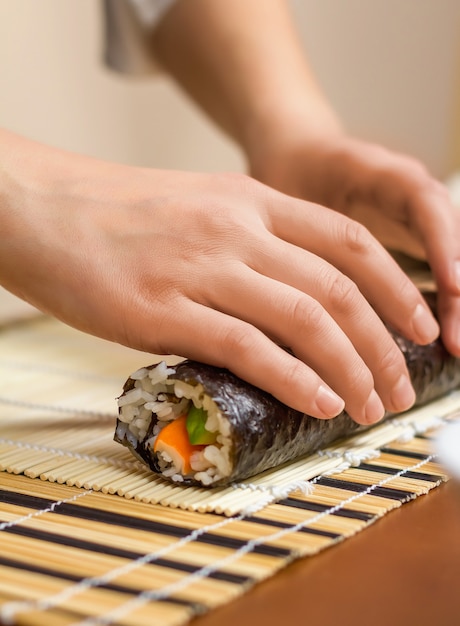Hands of woman chef rolling up a japanese sushi