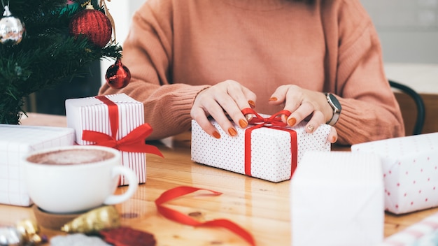 Hands of woman decorating Christmas and New Year gift box.