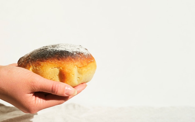 Hands of a woman holding freshly baked bread at home close up. White background. Space for text