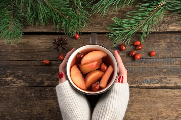 クリスマスの飲み物とマグカップを持っている女性の手。