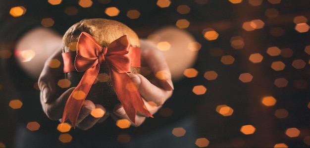 Hands Woman holding panettone wrapped as a christmas gift close up