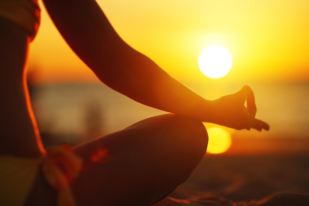 Photo hands of woman meditating in a yoga pose at sunset on the beach