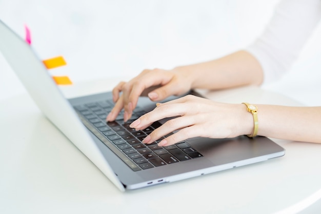 Hands of a woman operating a laptop in a bright room