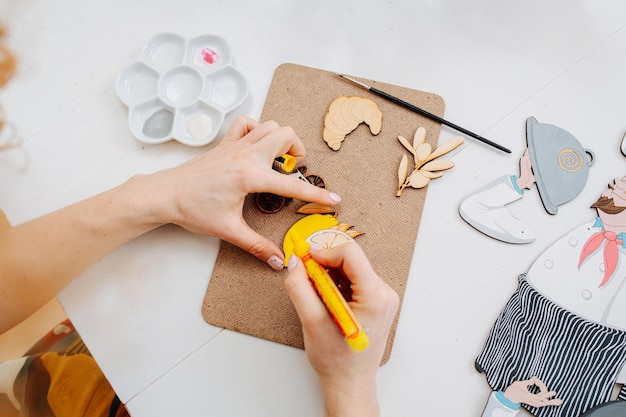 Hands of a woman painting wooden shapes with a yellow felt tip pen