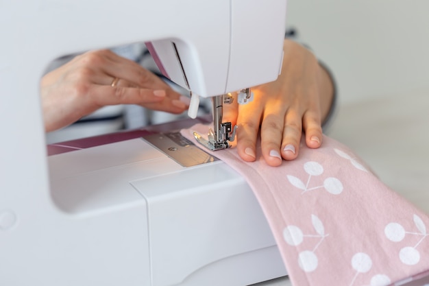 Hands of a woman seamstress sew a new product on a sewing machine