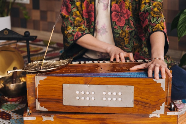 Hands of a woman sitting on the floor and playing the harmonium during the practice of kundalini yoga